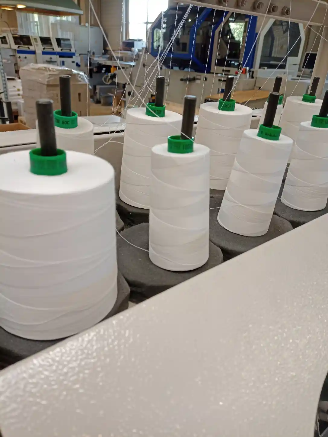 Garnspulen und Fäden an einer industriellen Maschine zur Buchbindung.